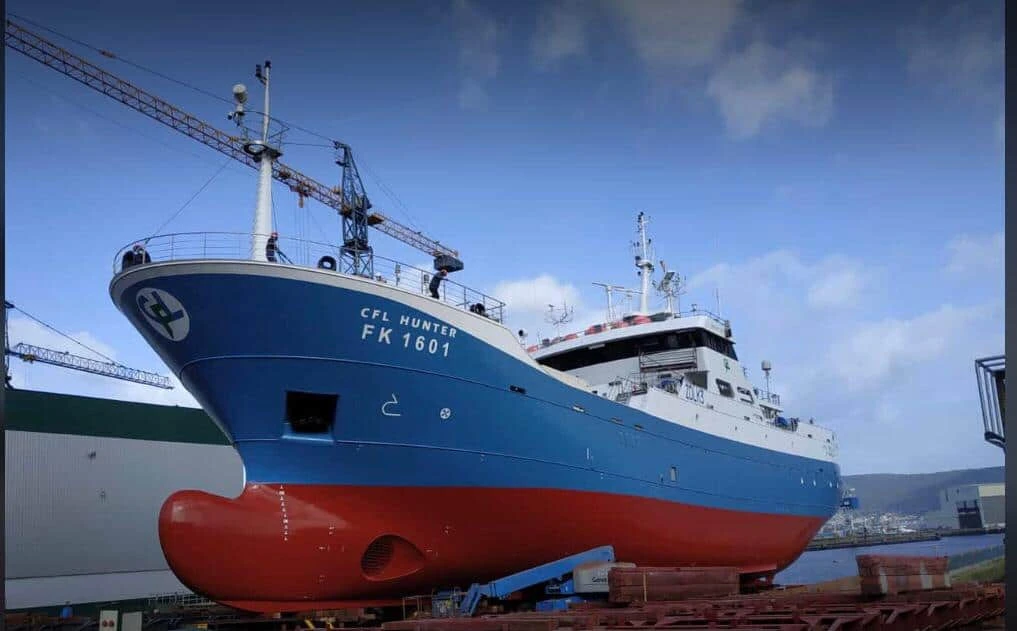 Fishing vessel in dry dock at a shipyard for maintenance and inspection.