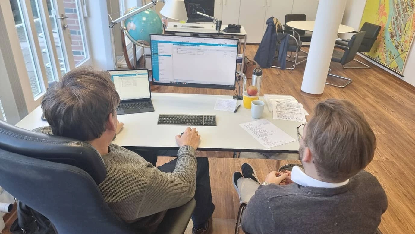 Shore-based maritime team reviewing fleet management software in office environment.
