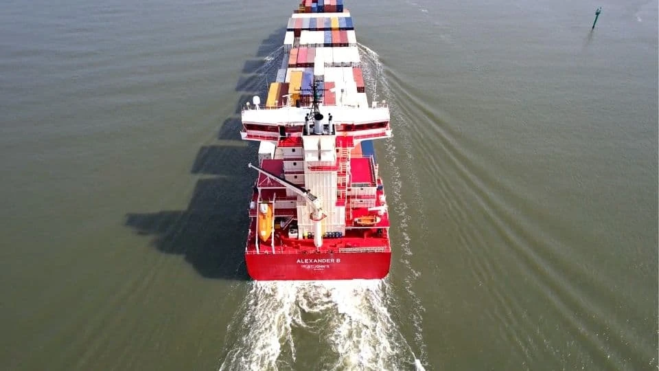Aerial view of a container vessel sailing along an inland waterway.