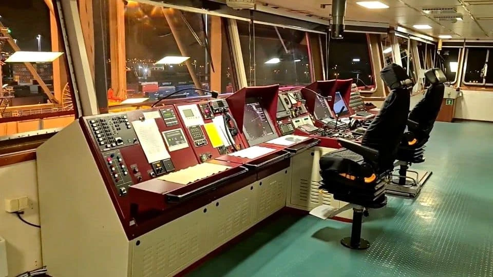 Ship bridge with navigation equipment and control consoles during night operations.