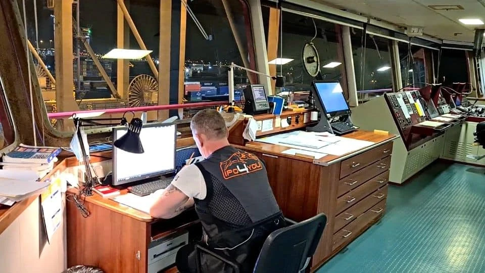 Crew member working at a computer inside the ship bridge during night operations.