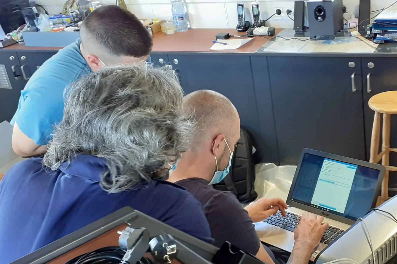 Crew members receiving training on maritime management software using a laptop.